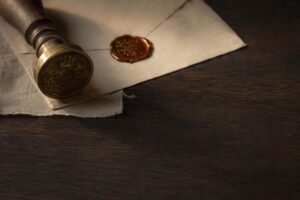 Sello oficial antiguo de bronce y sobre cerrado con sello de lacre sobre mesa de madera, evocando el trámite de cancelación de antecedentes penales