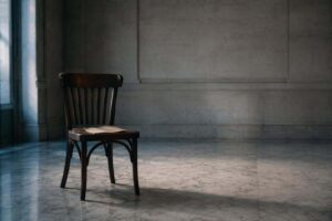 Silla vacía de madera oscura con una hoja de papel sobre el asiento en una sala vacía, evocando la ausencia del acusado en el juicio penal
