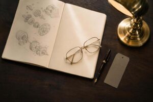 Cuaderno abierto con esquemas técnicos a lápiz y gafas de diseño sobre escritorio de despacho, ilustrando los delitos contra la propiedad industrial