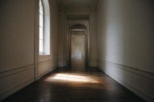Pasillo institucional vacío al amanecer con luz lateral, escena sobria sobre la prisión permanente revisable